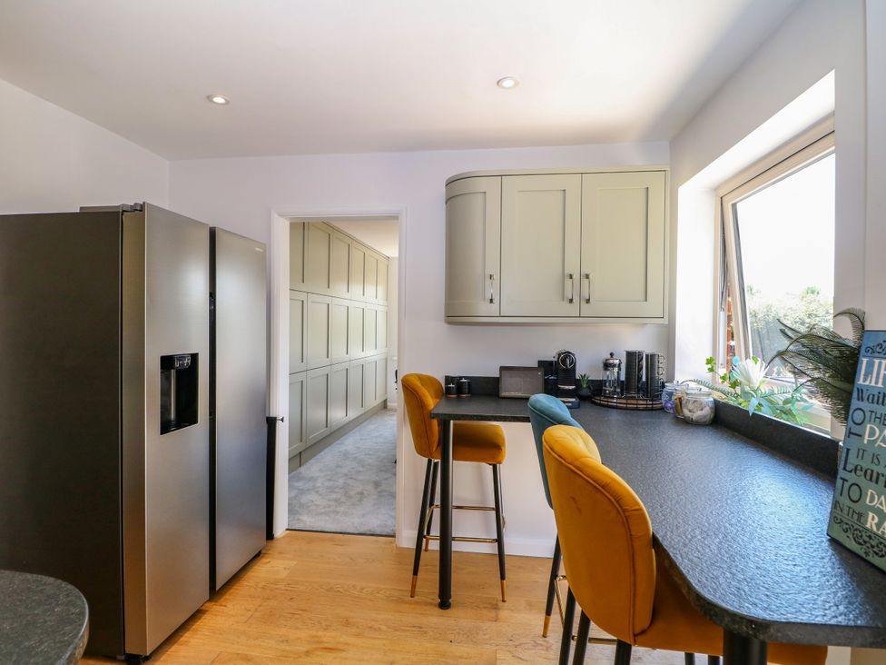A kitchen with a refrigerator and bar stools at Perry Dees in Minstead