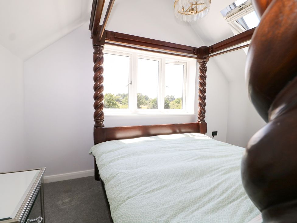 A bedroom with a four-poster bed and windows at Perry Dees in Minstead