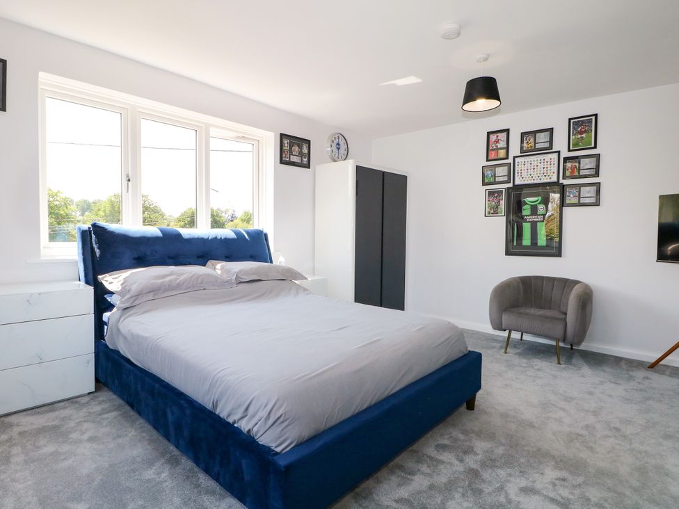 A bedroom with a blue bed and a chair at Perry Dees in Minstead