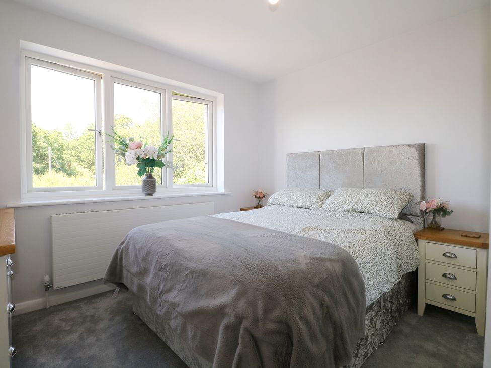 A bedroom with a bed and windows at Perry Dees in Minstead