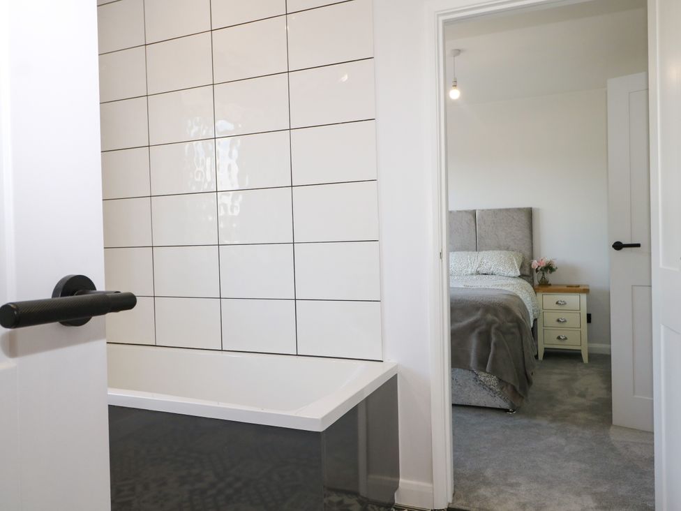 A bathroom with a bathtub and a bedroom in the background at Perry Dees Minstead