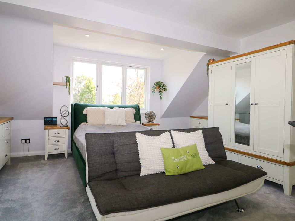 A bedroom with a bed, sofa bed, dresser, and windows at Perry Dees in Minstead