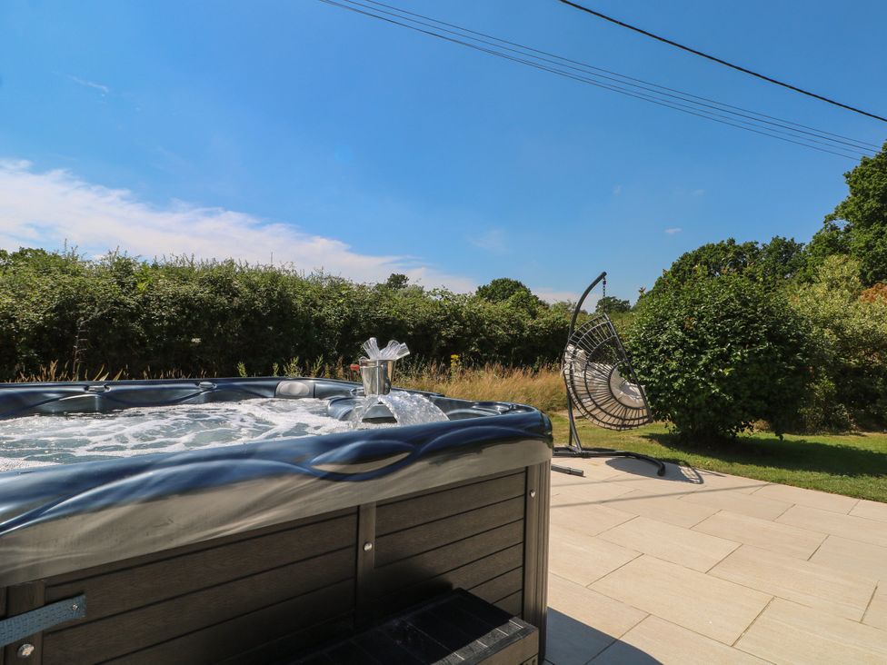 A hot tub with a hanging chair in the garden at Perry Dees in Minstead