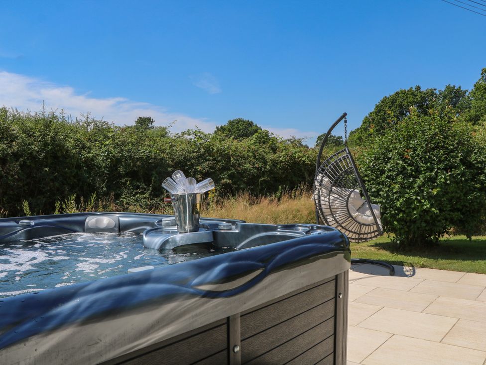 A hot tub with an ice bucket and a hanging chair in an outdoor area at Perry Dees in Minstead