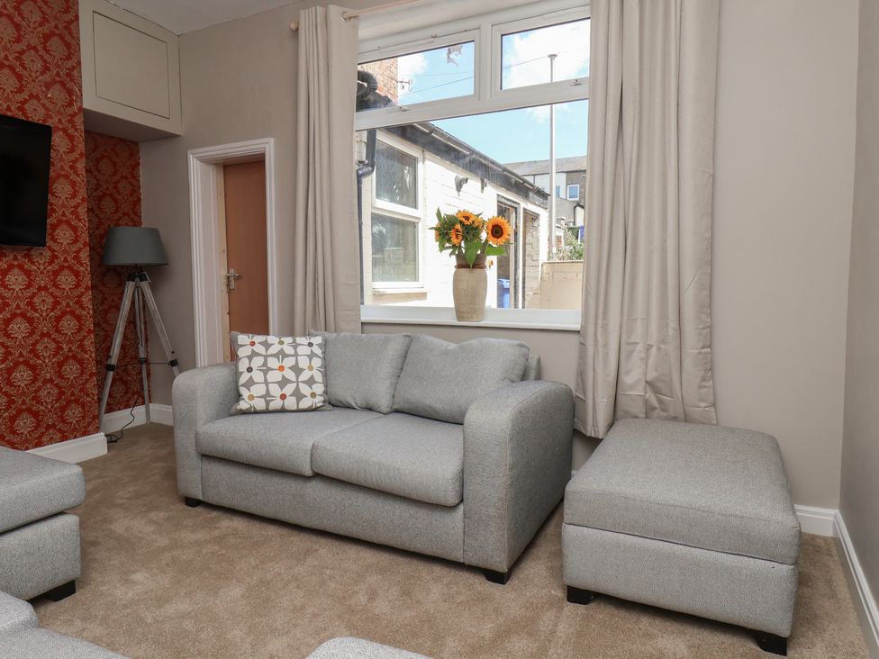 A living room with a sofa and flowers in a vase at Lansdowne Grange in Bridlington