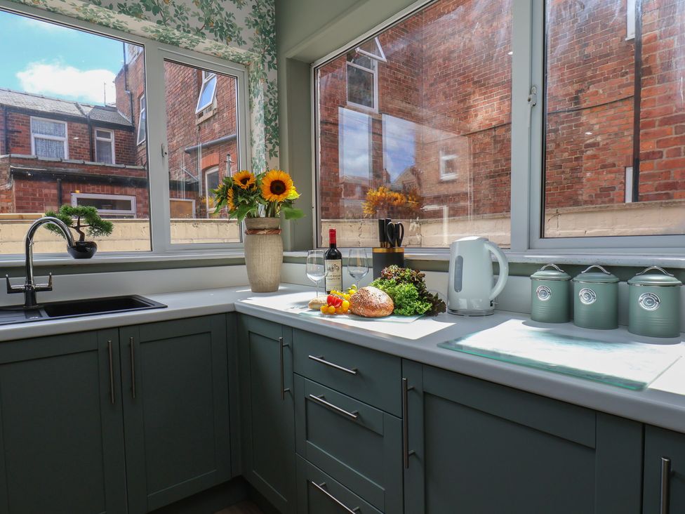 A kitchen with a sink, window and various items including wine at Lansdowne Grange in Bridlington