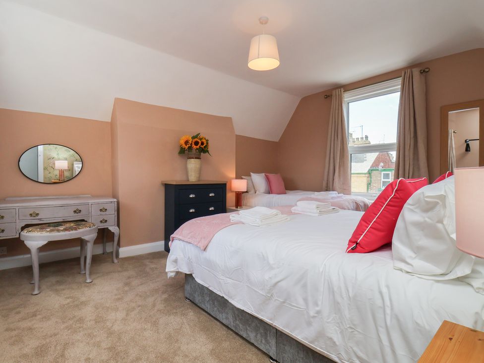A bedroom with two beds and a dressing table at Lansdowne Grange in Bridlington