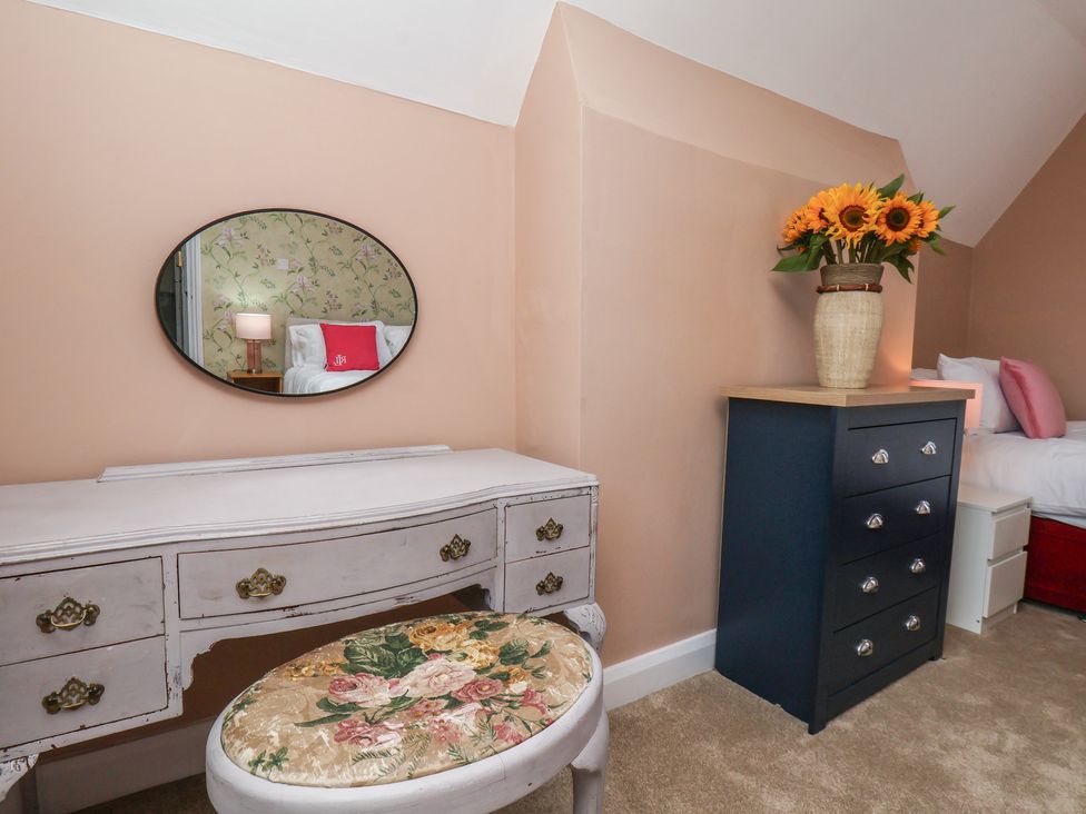 A bedroom with a mirror, table, and flowers at Lansdowne Grange in Bridlington
