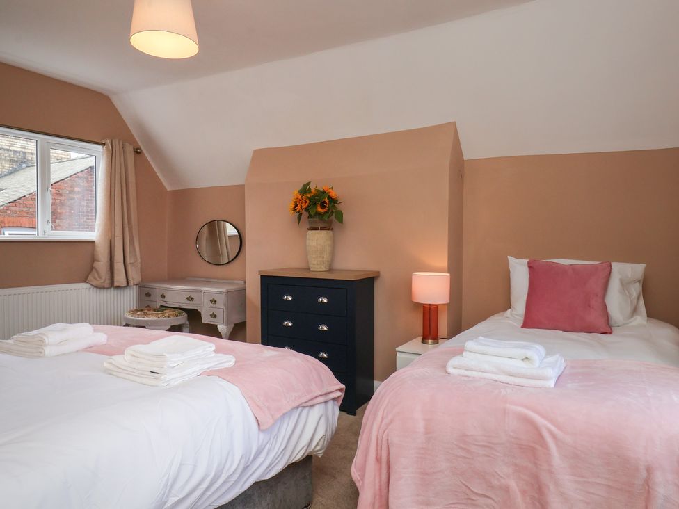 A bedroom with two beds, a dresser, and a mirror at Lansdowne Grange in Bridlington