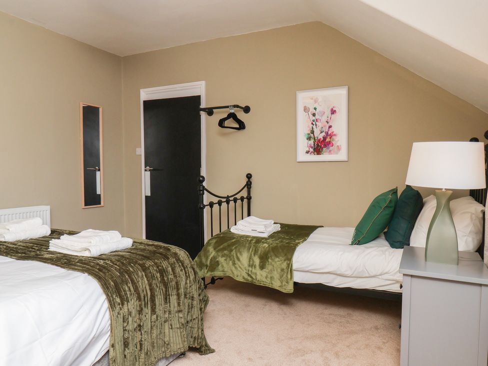 A bedroom with two beds and a bedside table at Lansdowne Grange in Bridlington