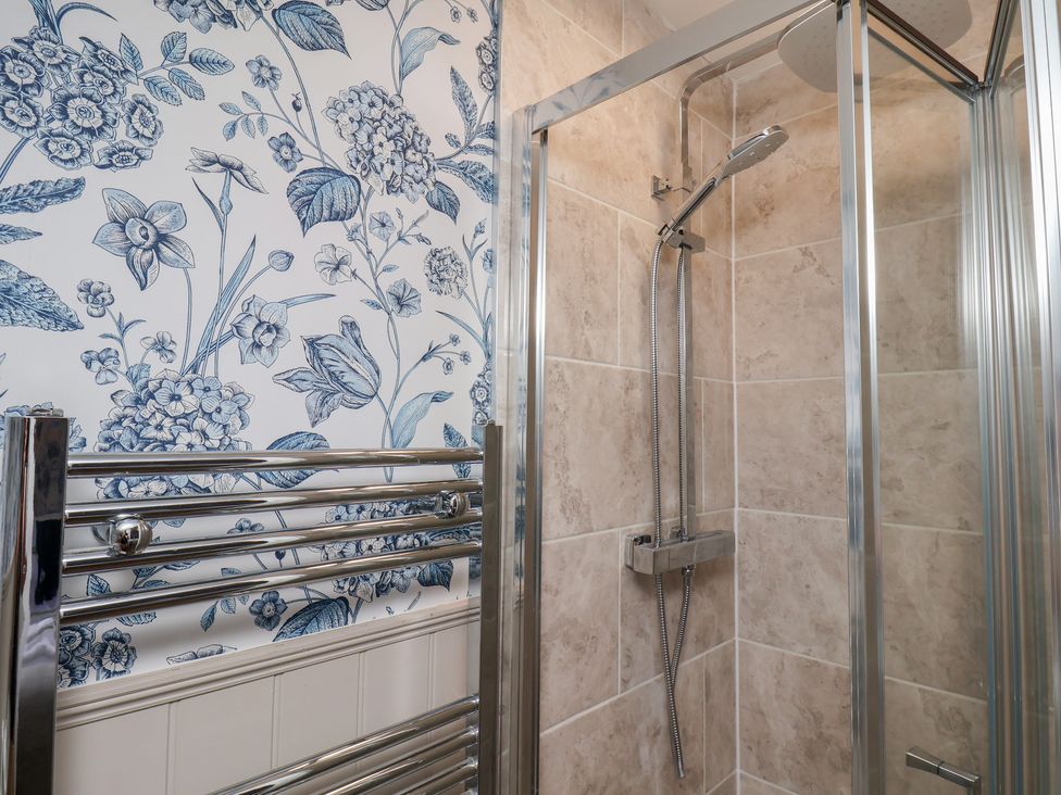 A bathroom with a shower and floral wallpaper at Lansdowne Grange in Bridlington
