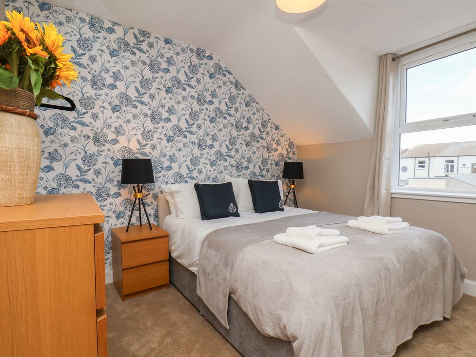 A bedroom with a bed and floral wallpaper at Lansdowne Grange in Bridlington