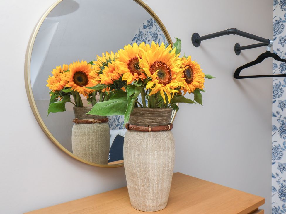 A vase with sunflowers next to a mirror in a room at Lansdowne Grange Bridlington