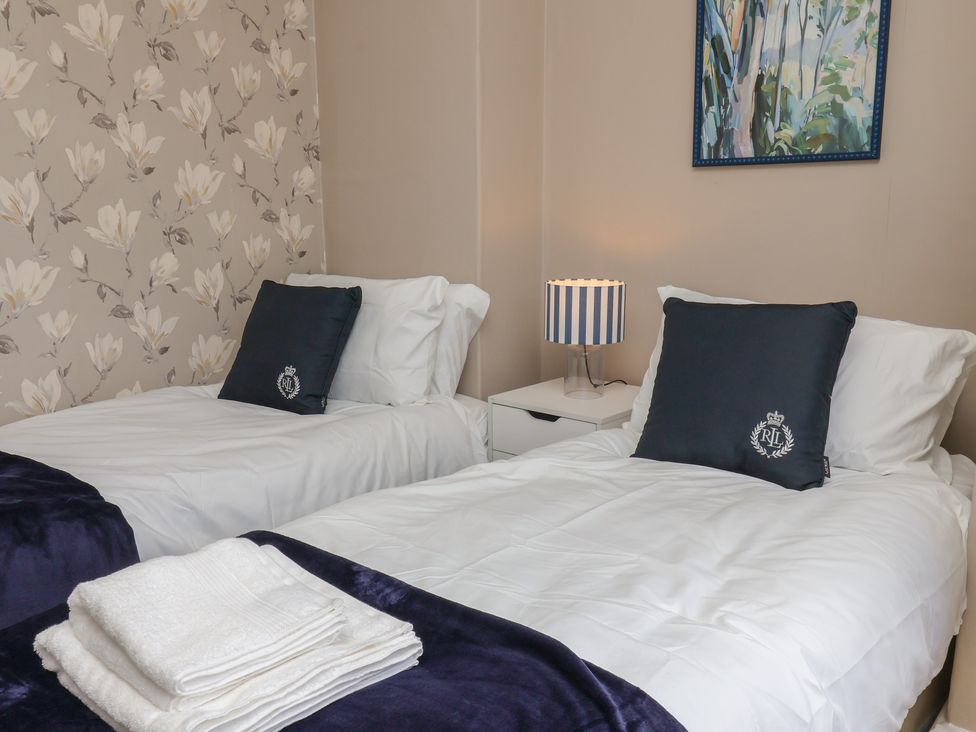 A bedroom with two beds and a nightstand at Lansdowne Grange Bridlington
