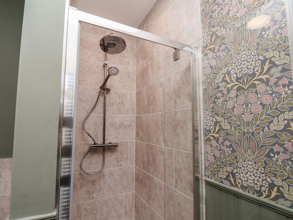 A shower with a shower head and tiled walls at Lansdowne Grange in Bridlington