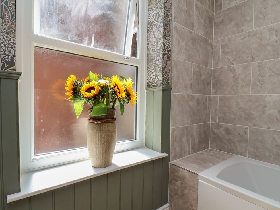 A bathroom with a bathtub and flowers on a windowsill at Lansdowne Grange in Bridlington