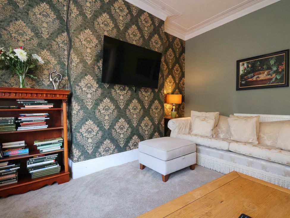 A living room with a sofa, television, and bookshelf at Lansdowne Grange in Bridlington
