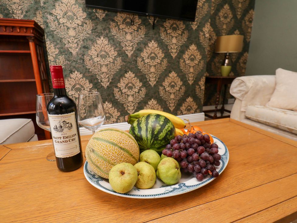 A table with fruits and wine in a living room at Lansdowne Grange in Bridlington