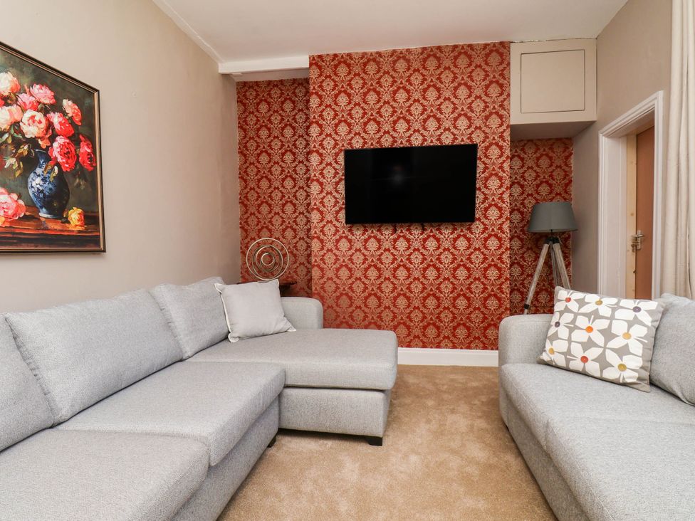 A living room with a grey sofa and television at Lansdowne Grange in Bridlington