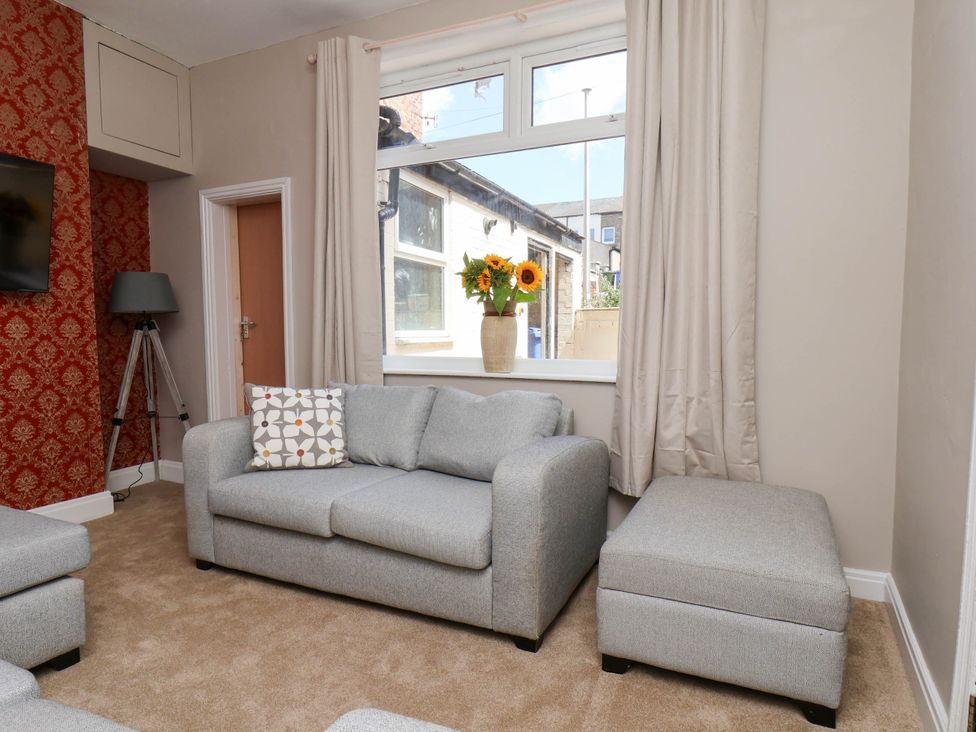 A living room with a sofa and flowers on a window sill at Lansdowne Grange in Bridlington