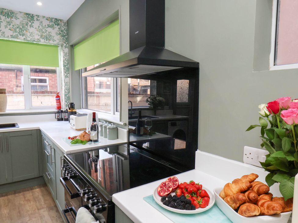 A kitchen with a sink, oven, and bowl of fruits at Lansdowne Grange in Bridlington
