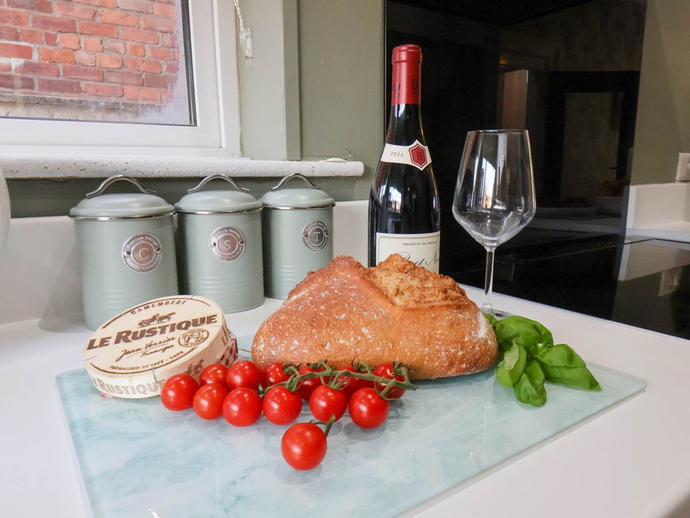 A kitchen counter with bread, tomatoes, wine, and cheese at Lansdowne Grange in Bridlington