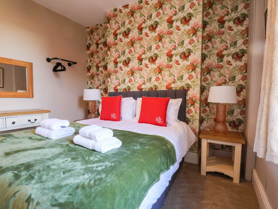 A bedroom with a bed and decorative wallpaper at Lansdowne Grange in Bridlington