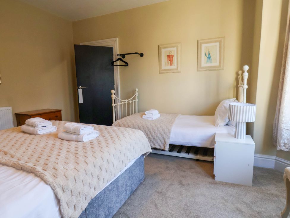 A bedroom with two beds and a bedside table at Lansdowne Grange in Bridlington