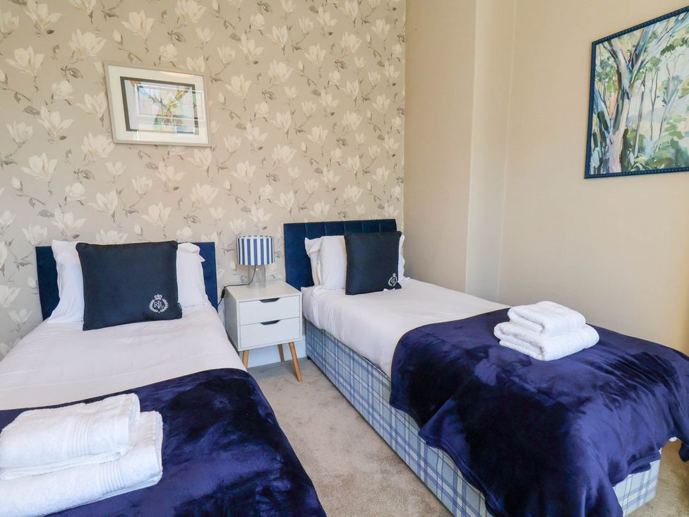 A bedroom with two beds and a bedside table at Lansdowne Grange in Bridlington