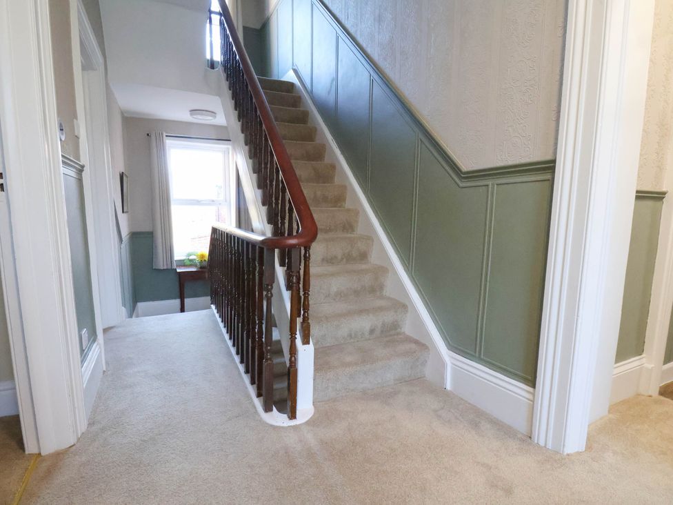 A hallway with a staircase and window at Lansdowne Grange in Bridlington