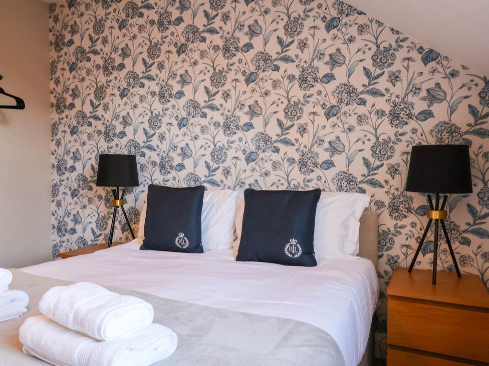A bedroom with a double bed and decorative wallpaper at Lansdowne Grange in Bridlington