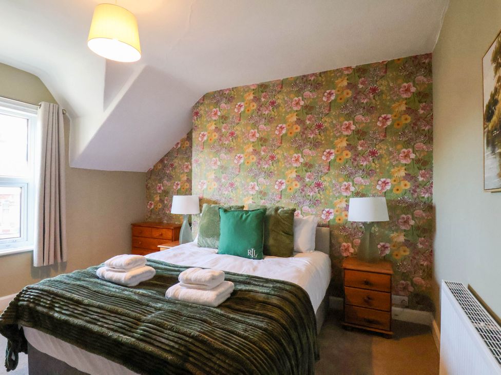 A bedroom with a bed, nightstands, and a window at Lansdowne Grange in Bridlington