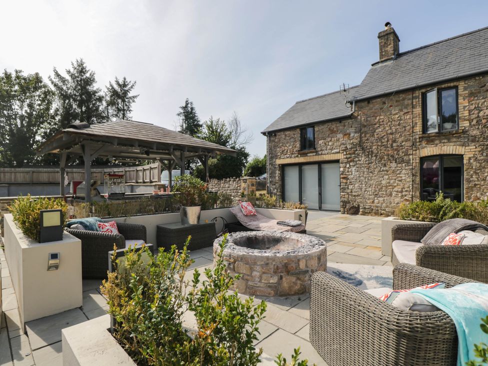 An outdoor seating area with a firepit and kitchen at Llanfarach Farmhouse near Pontyclun