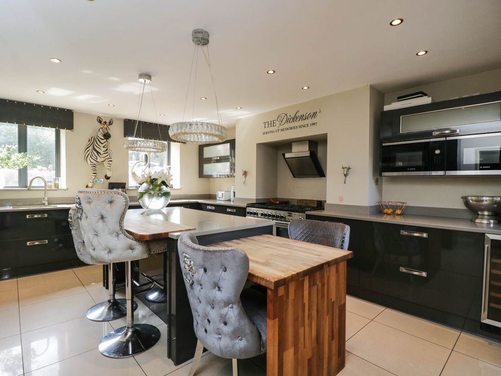 A kitchen with a dining table and bar stools at Llanfarach Farmhouse near Pontyclun