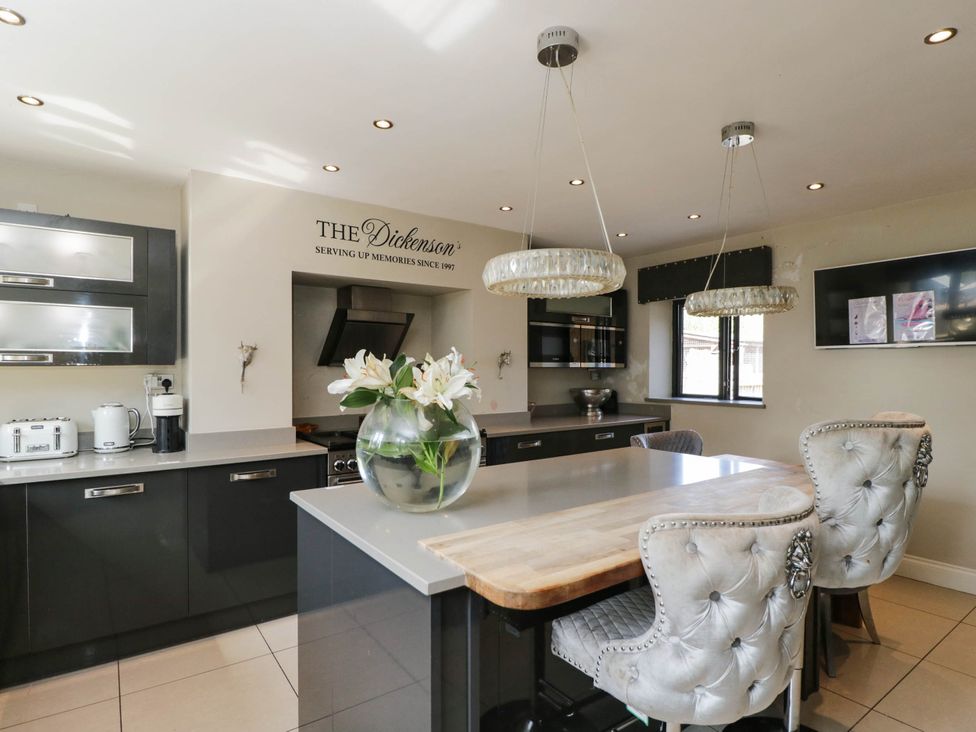 A kitchen with a dining island and chairs at Llanfarach Farmhouse near Pontyclun