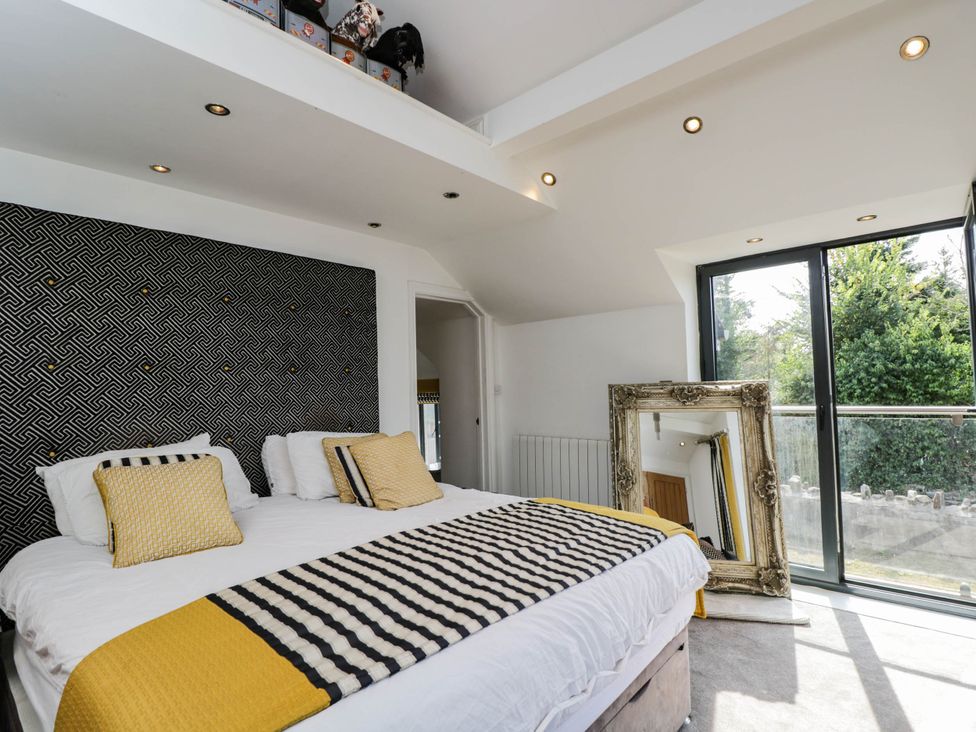 A bedroom with a bed and a large mirror at Llanfarach Farmhouse near Pontyclun