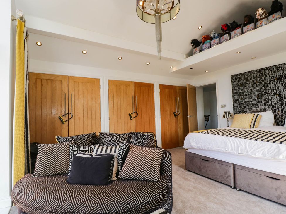A bedroom with a bed and an armchair at Llanfarach Farmhouse near Pontyclun