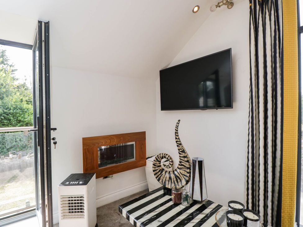 A living room with a television and decorative items at Llanfarach Farmhouse near Pontyclun