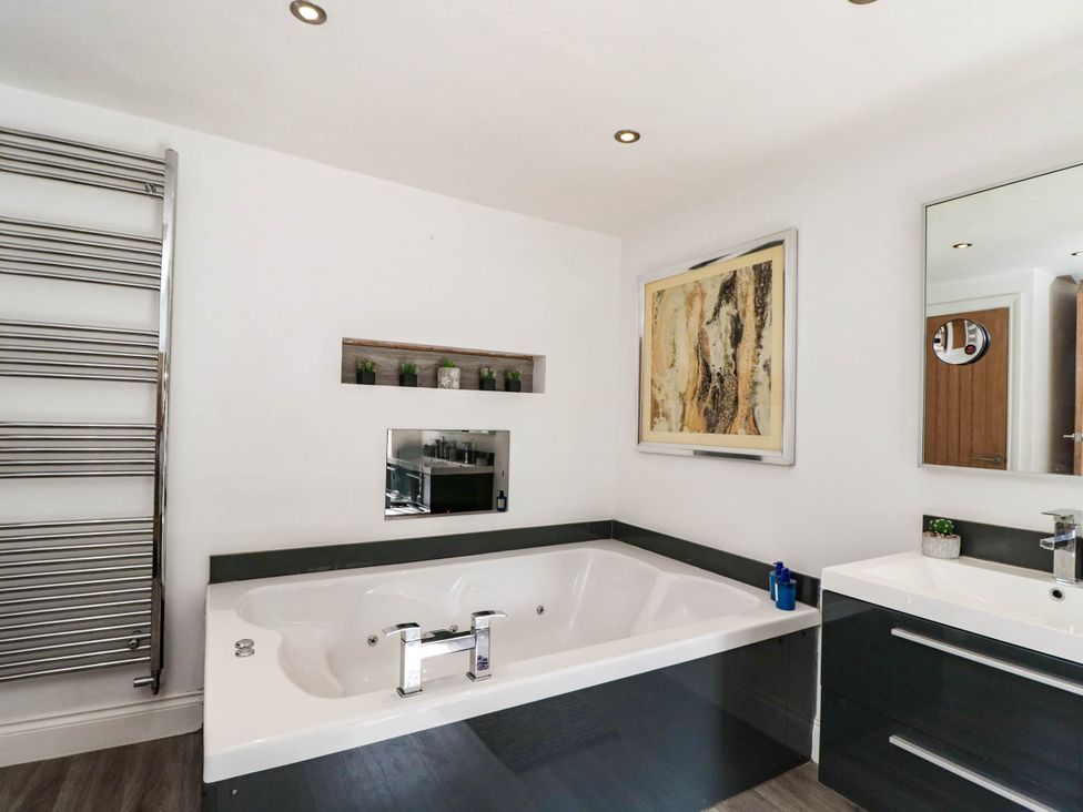 A bathroom featuring a bathtub, sink, and towel radiator at Llanfarach Farmhouse near Pontyclun