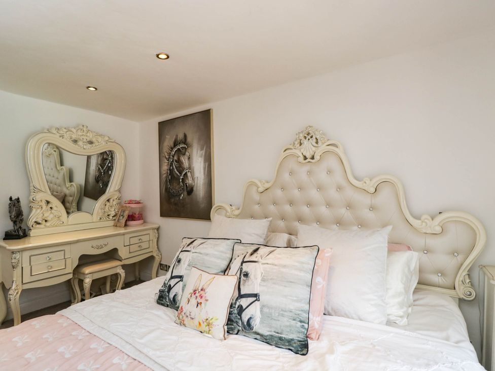 A bedroom with a bed and dressing table at Llanfarach Farmhouse near Pontyclun