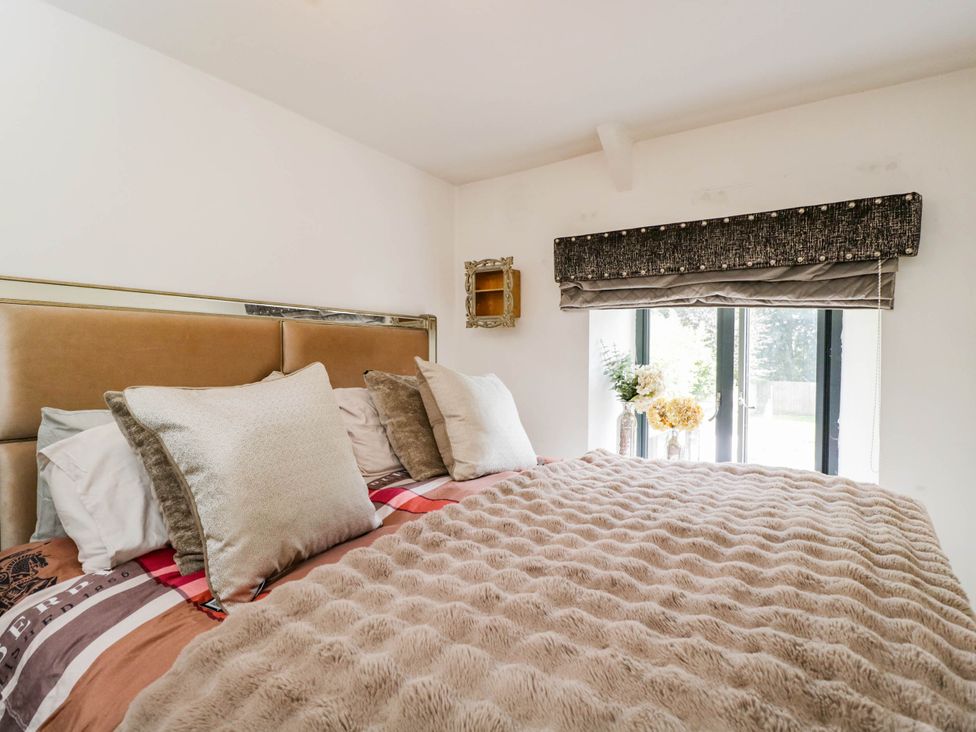 A bedroom with a bed and window at Llanfarach Farmhouse near Pontyclun