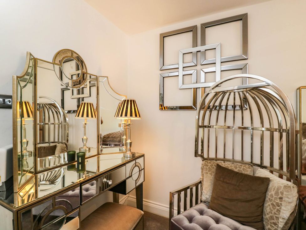 A dressing room with a mirror, lamp, and chair at Llanfarach Farmhouse near Pontyclun