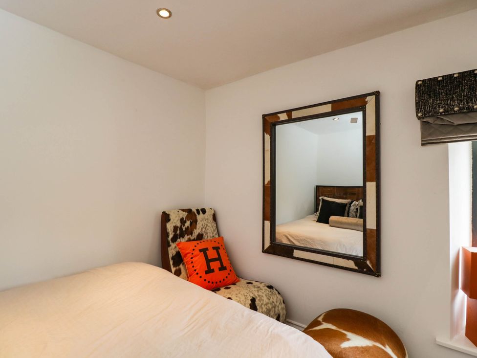 A bedroom with a bed and a mirror at Llanfarach Farmhouse near Pontyclun