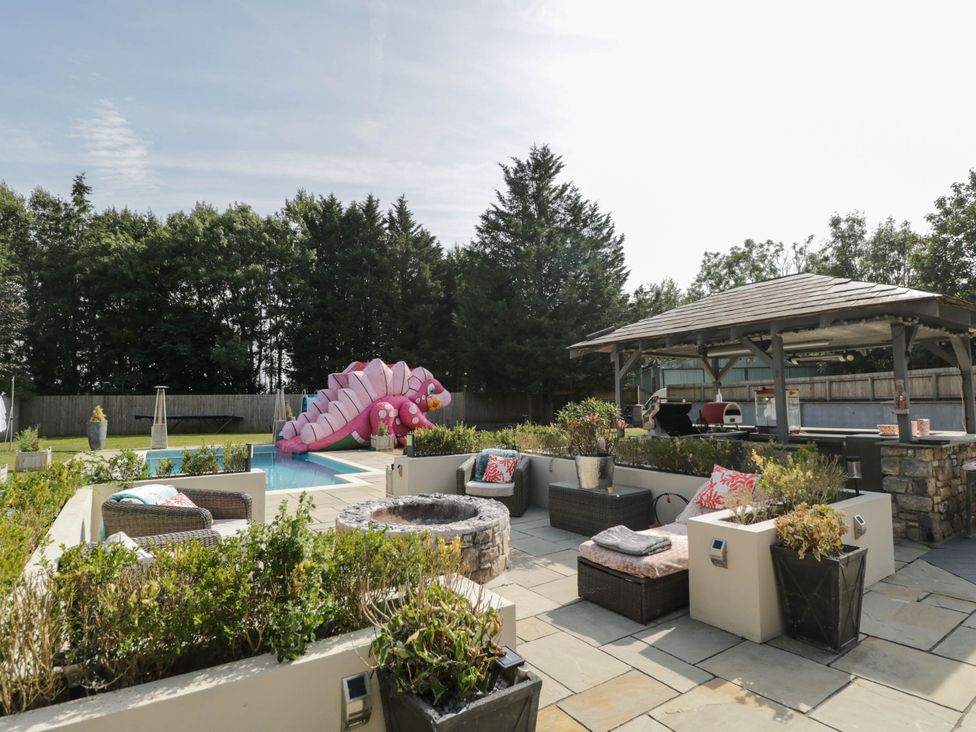 An outdoor area with a pool and seating at Llanfarach Farmhouse near Pontyclun