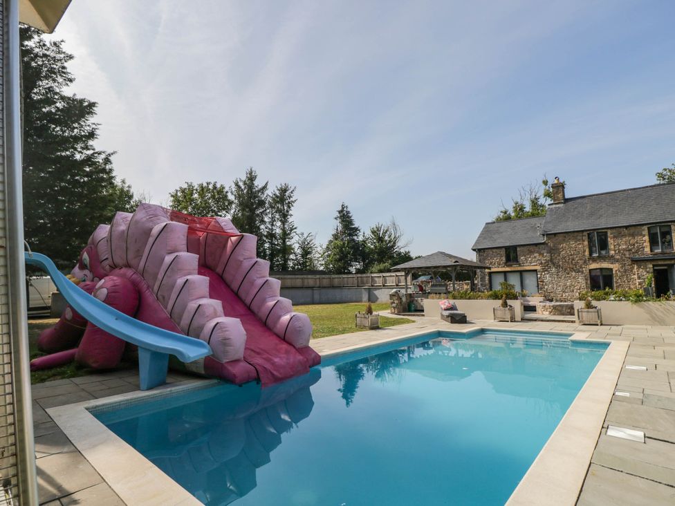An outdoor area with a swimming pool and water slide at Llanfarach Farmhouse near Pontyclun
