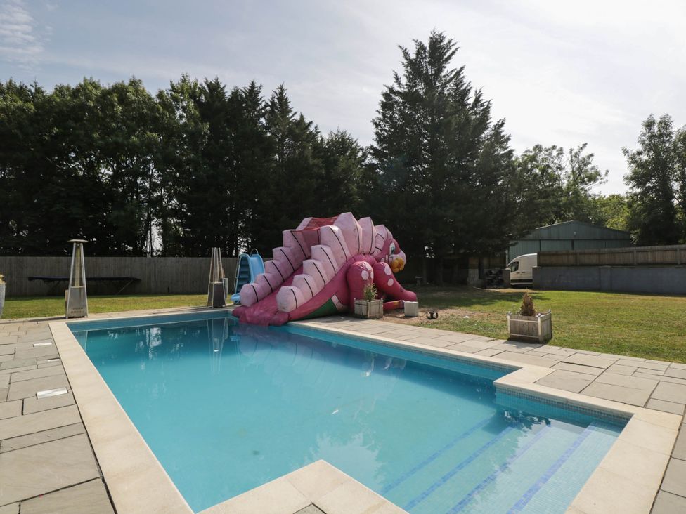 An outdoor area with a swimming pool and inflatable slide at Llanfarach Farmhouse near Pontyclun