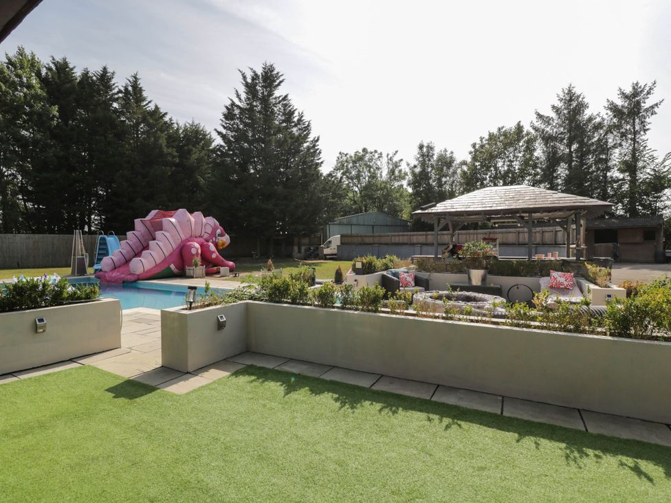 A garden with a swimming pool and slide at Llanfarach Farmhouse near Pontyclun
