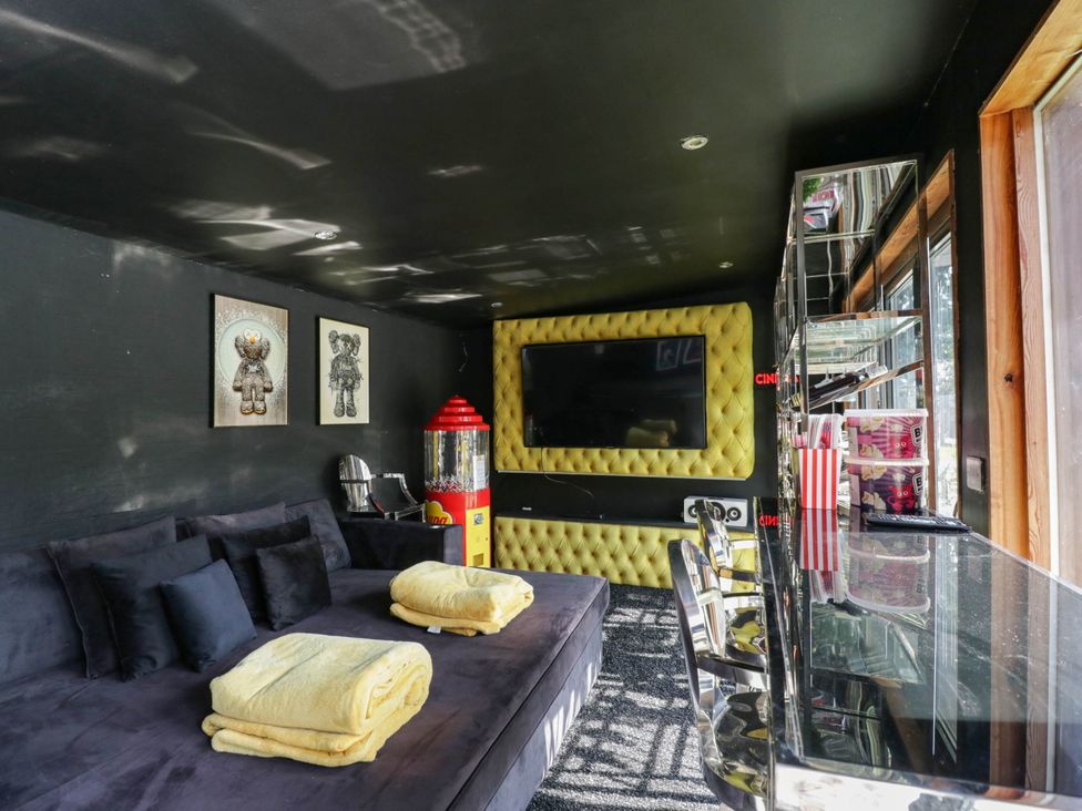 A snug with a couch, television, and popcorn machine at Llanfarach Farmhouse near Pontyclun