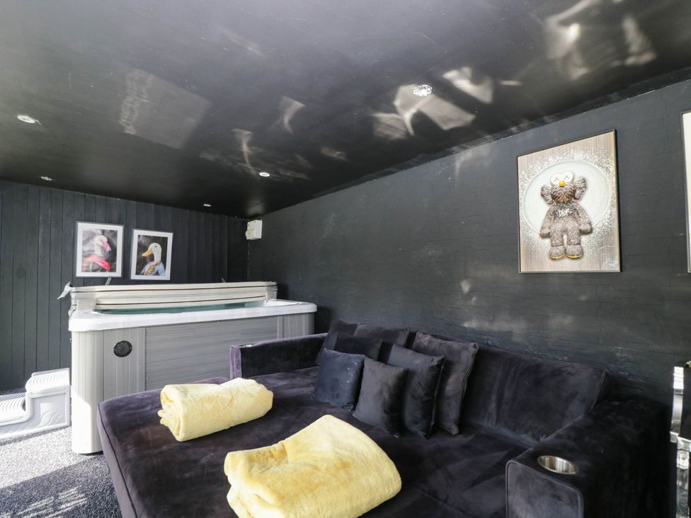 A snug with a hot tub and sofa at Llanfarach Farmhouse near Pontyclun