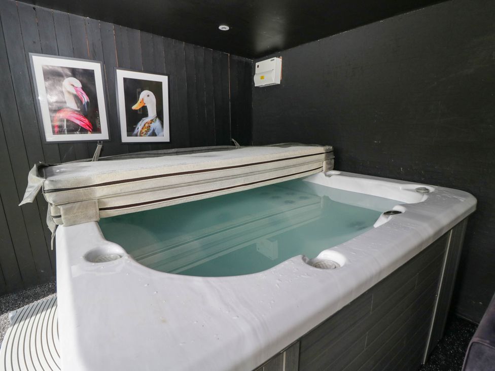 A hot tub with a cover and photographs on the wall at Llanfarach Farmhouse near Pontyclun